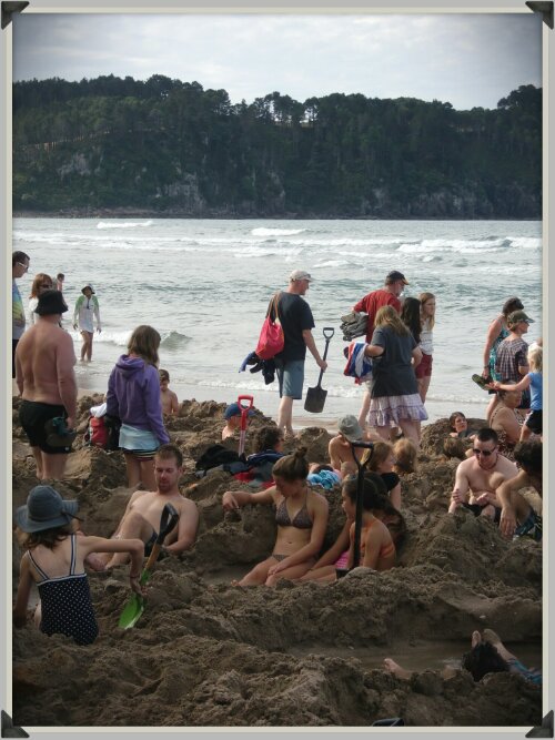 Touristes armés de pelles sur la plage de Hot Water Beach